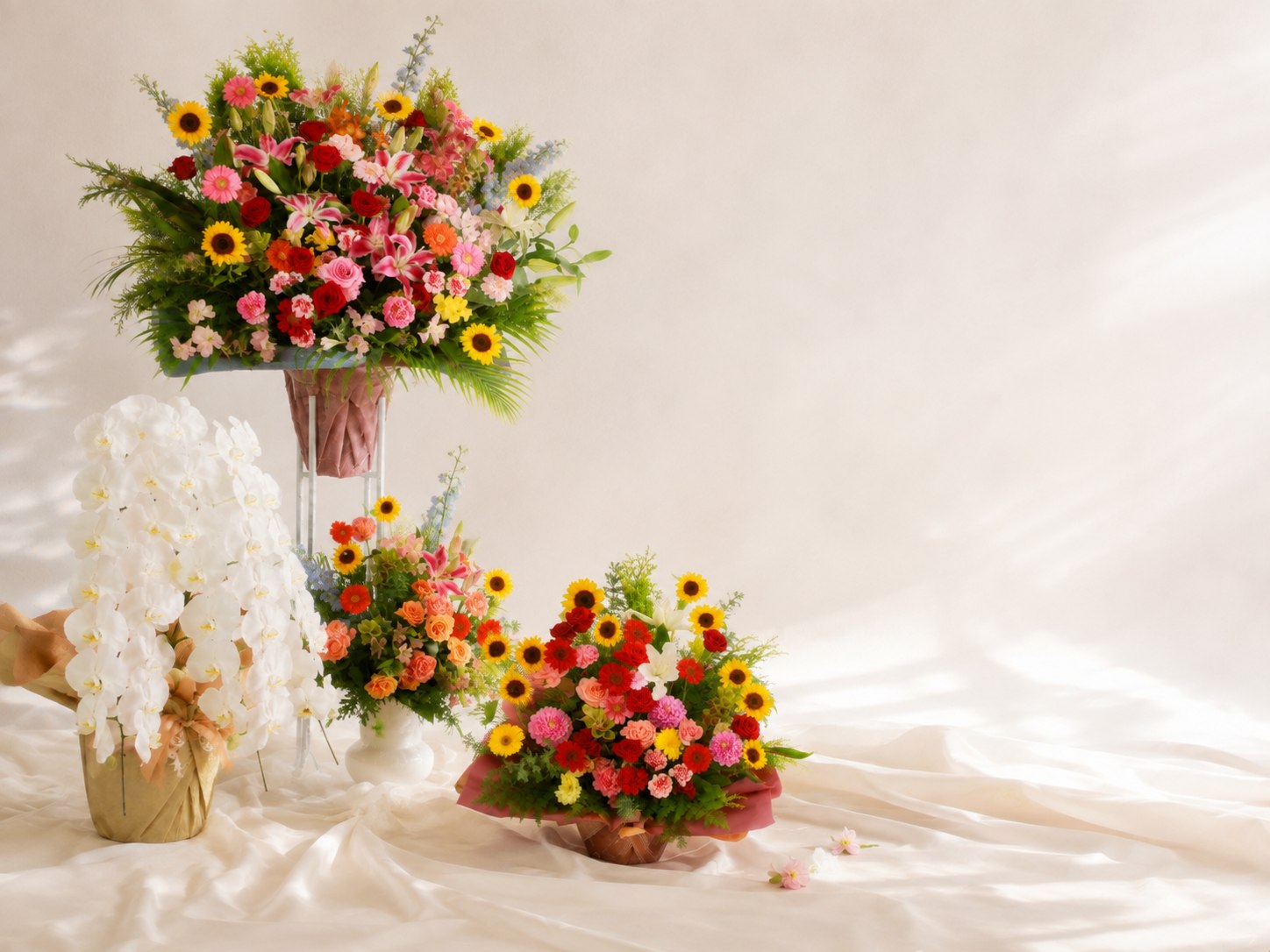 白い布を背景に、色とりどりの花束とアレンジメントを配した装花