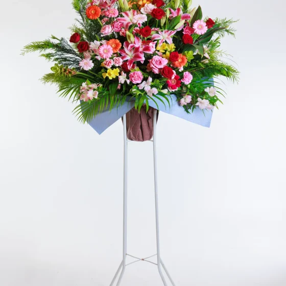 赤やピンクの花を中心にした一段の生花スタンド