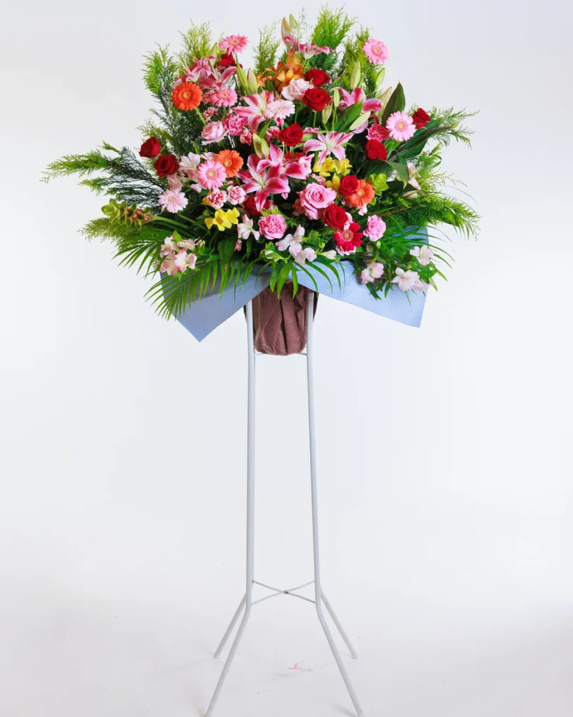 赤やピンクの花を中心にした一段の生花スタンド